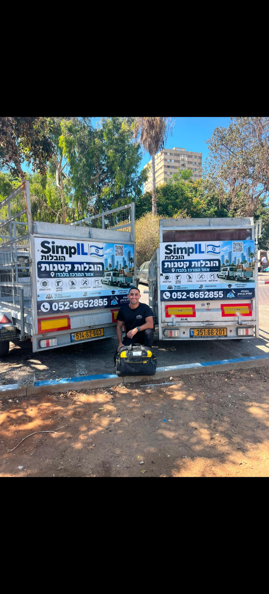 איש צוות SimpIL עם תיק כלי עבודה בין שני נגררי החברה